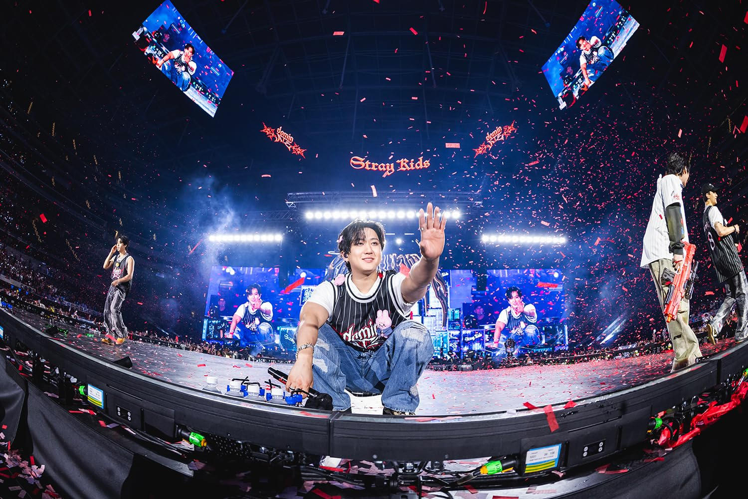 Ein K-Pop-Künstler winkt dem Publikum bei einem Konzert mit roten Konfetti.