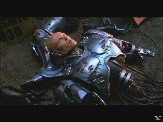 RoboCop liegt auf dem Boden, sein Kopf ist sichtbar, seine mechanischen Teile sind freigelegt.