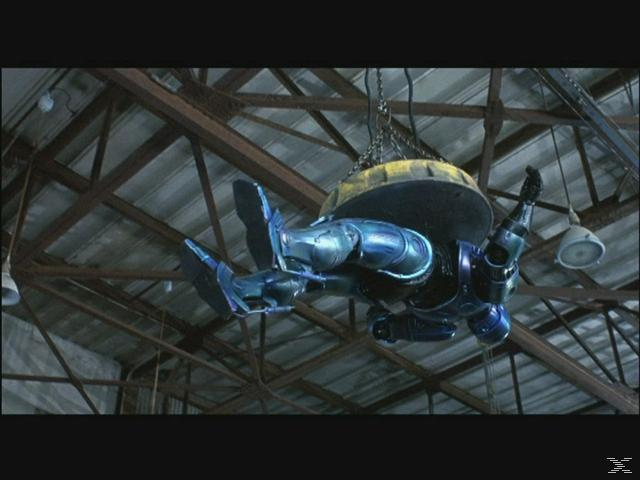 Ein blauer Roboter hängt an einem Magneten in einer Lagerhalle.