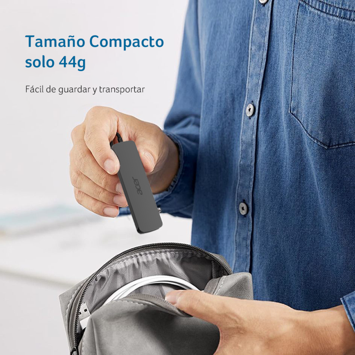Una mano sostiene un pequeño dongle gris de Acer sobre una bolsa gris abierta con cables.