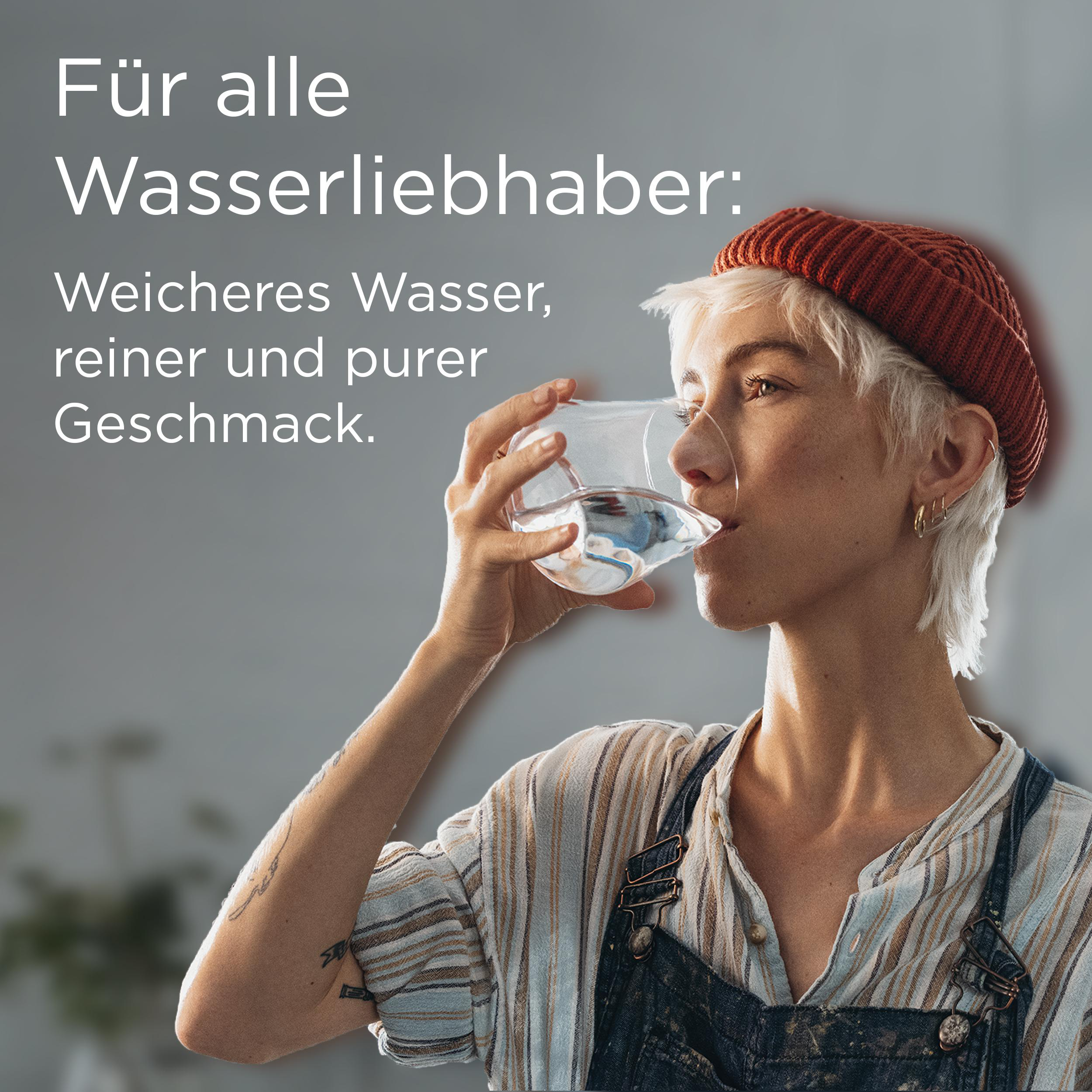 Eine Frau mit kurzen weißen Haaren trinkt aus einem Glas Wasser.