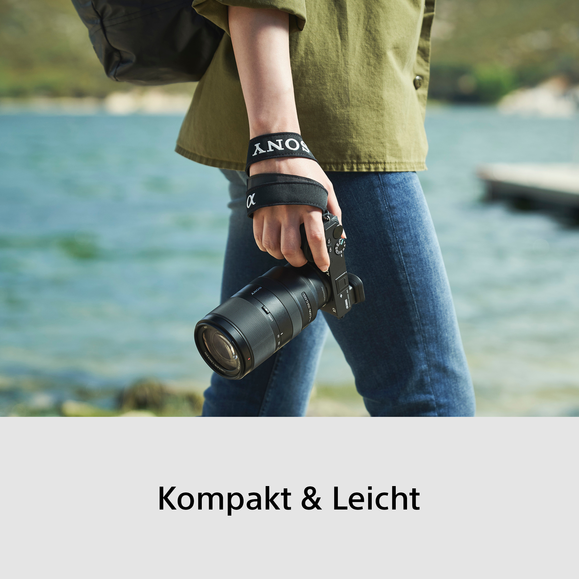 Eine Person im Freien hält eine Sony Kamera mit einem langen Objektiv.