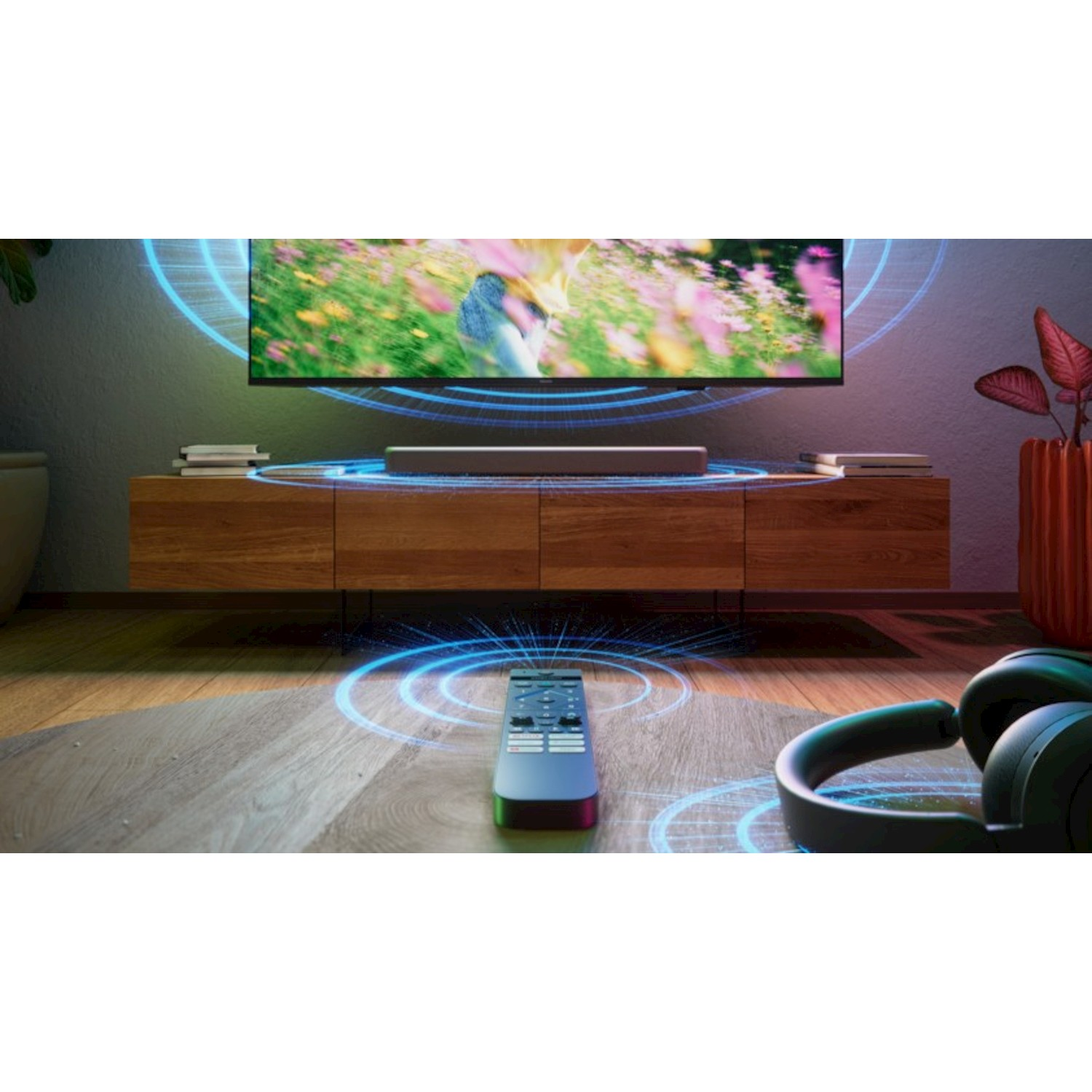 Un TV con soundbar, telecomando e cuffie su un pavimento in legno.