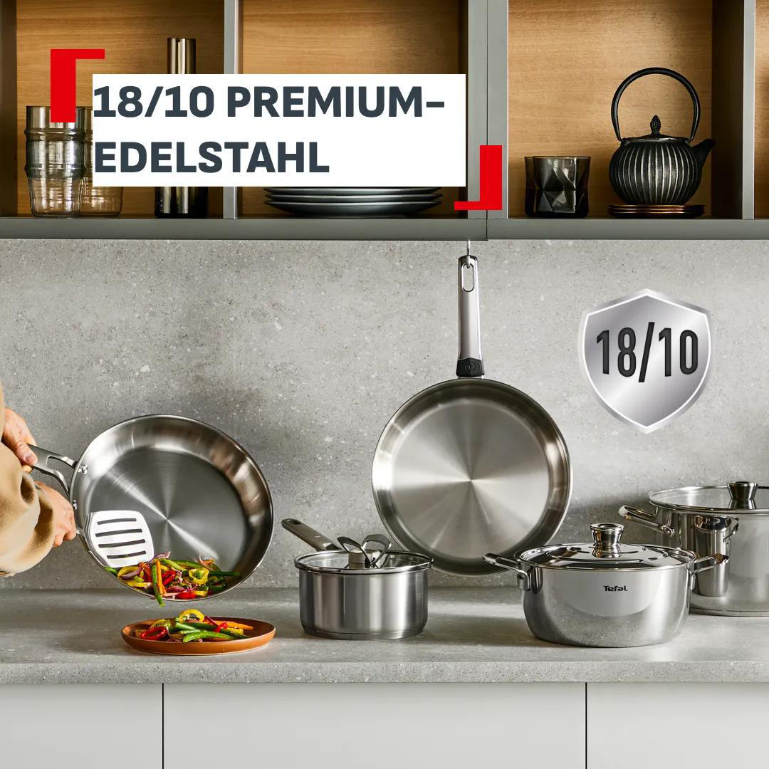 Edelstahlkochgeschirr, darunter Pfannen und Töpfe, auf einer Arbeitsplatte.
