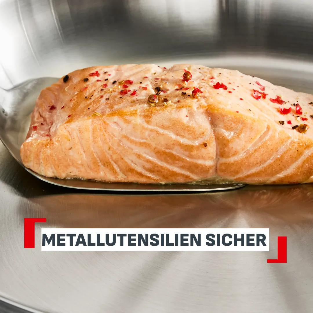 Ein gebratenes Lachsfilet mit Gewürzen in einer Metallpfanne.