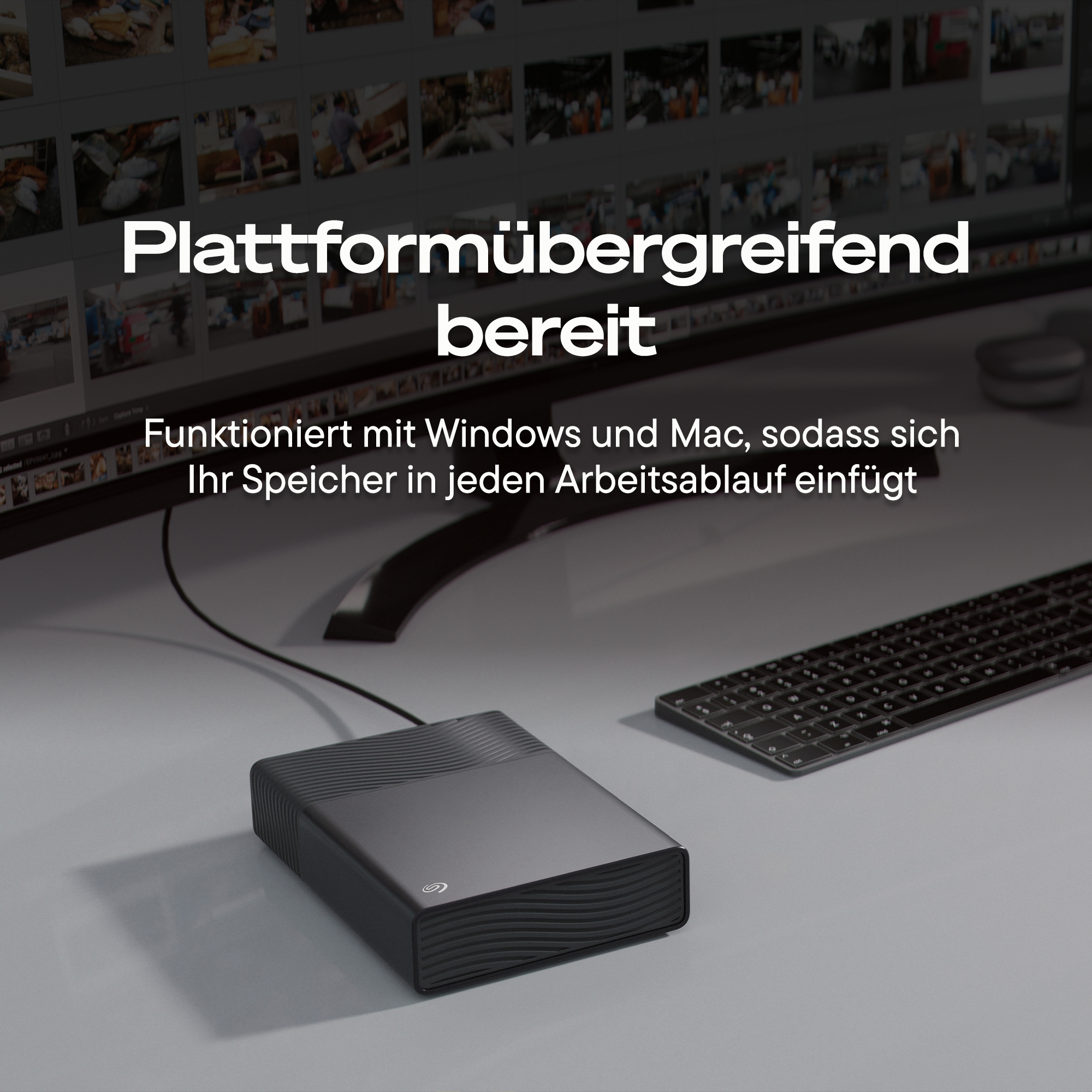 Ein externes Festplattenlaufwerk neben einer Tastatur vor einem Computermonitor.