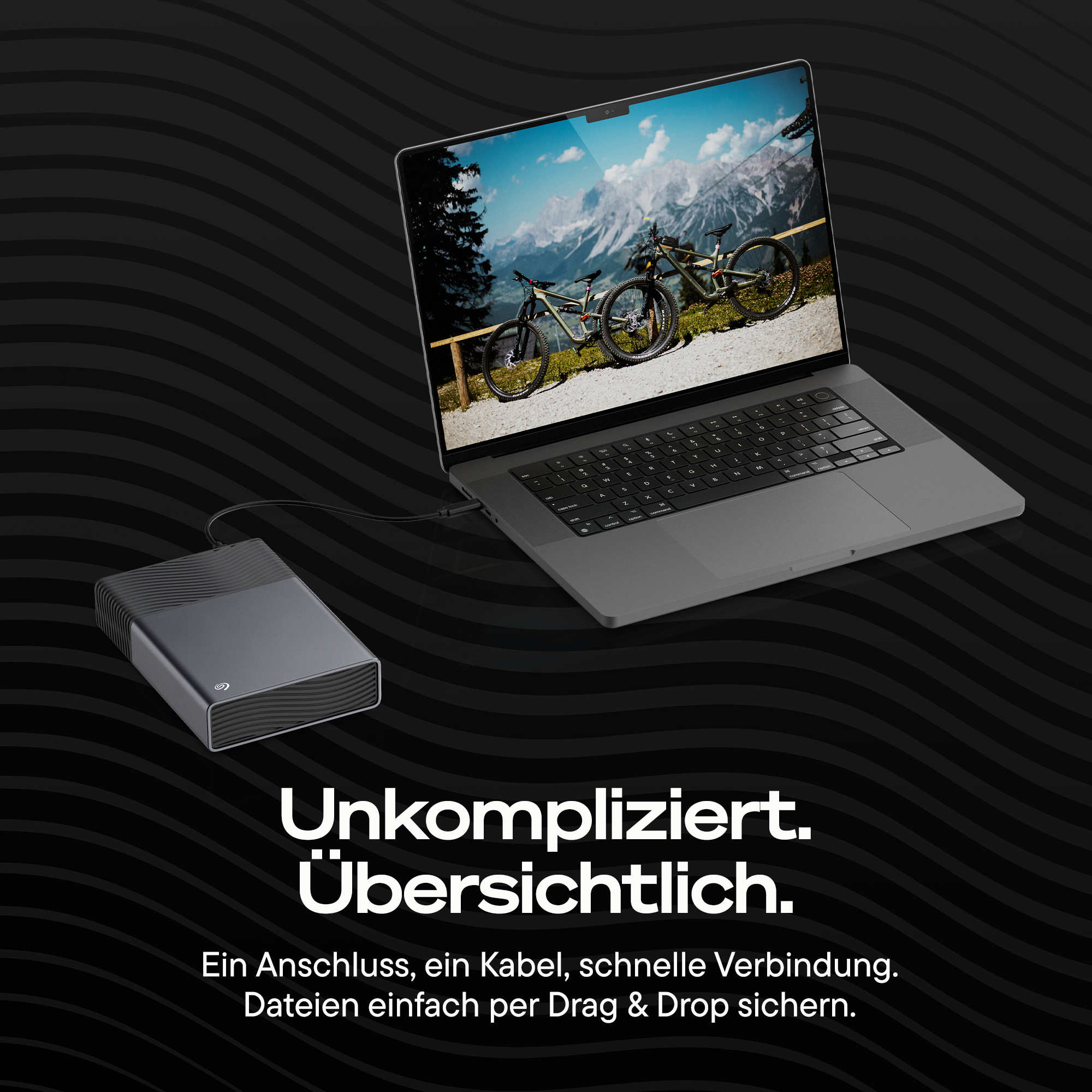 Ein Laptop mit externer Festplatte, zeigt Mountainbikes in den Bergen.