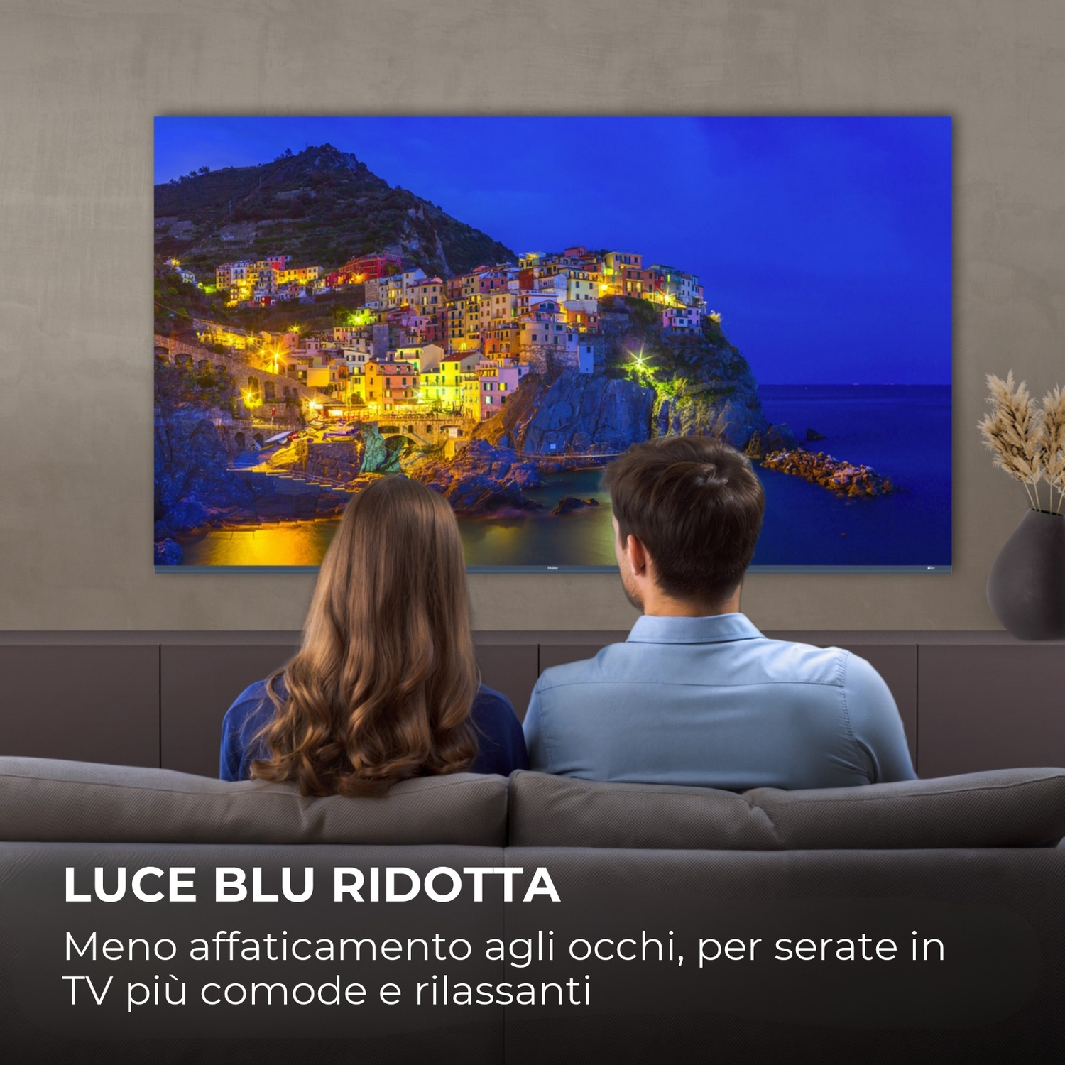 Coppia guarda un villaggio illuminato sul mare di notte.