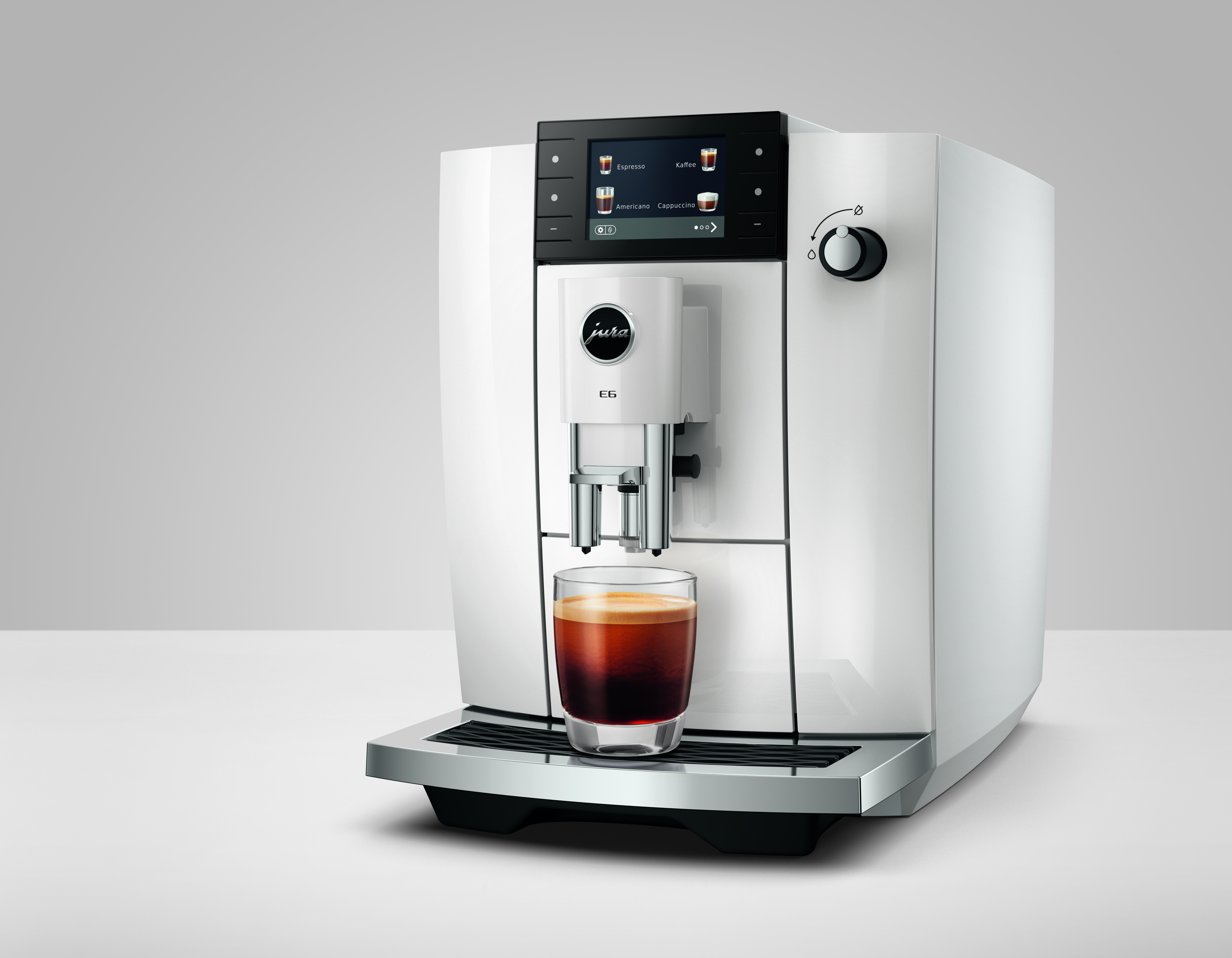 Eine weiße Kaffeemaschine mit einem Glas Espresso auf der Abtropffläche.
