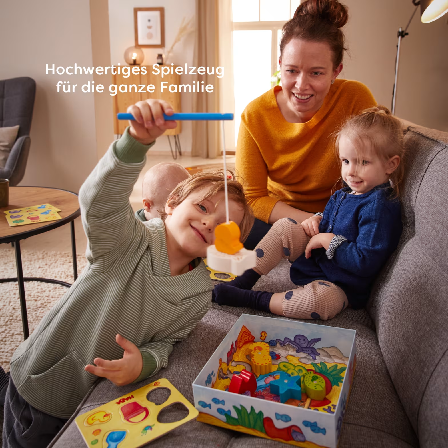 Anya és gyerekek HABA játékkal játszanak a nappaliban.