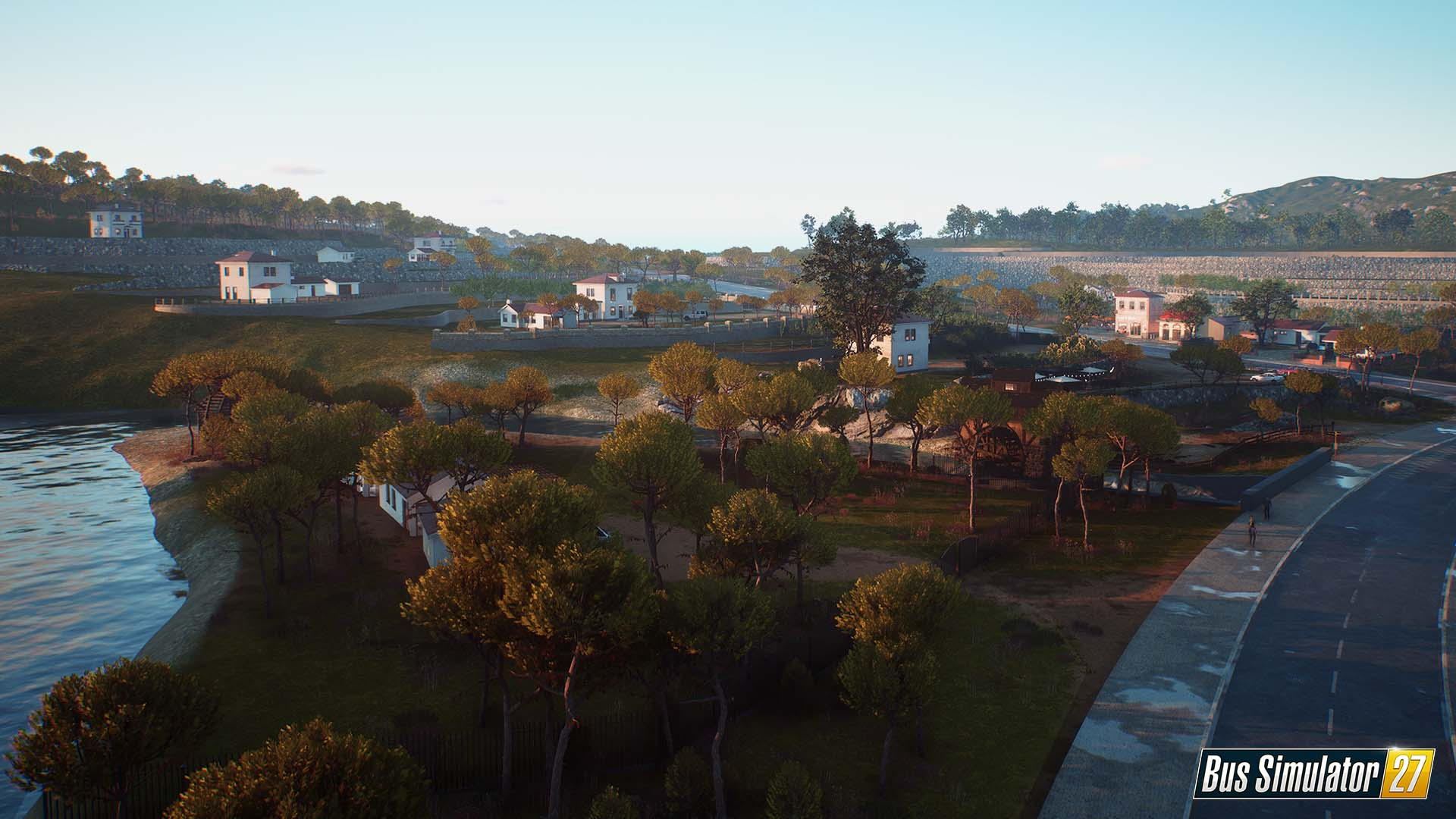 Día soleado en un pueblo costero con casas blancas, árboles y una carretera.