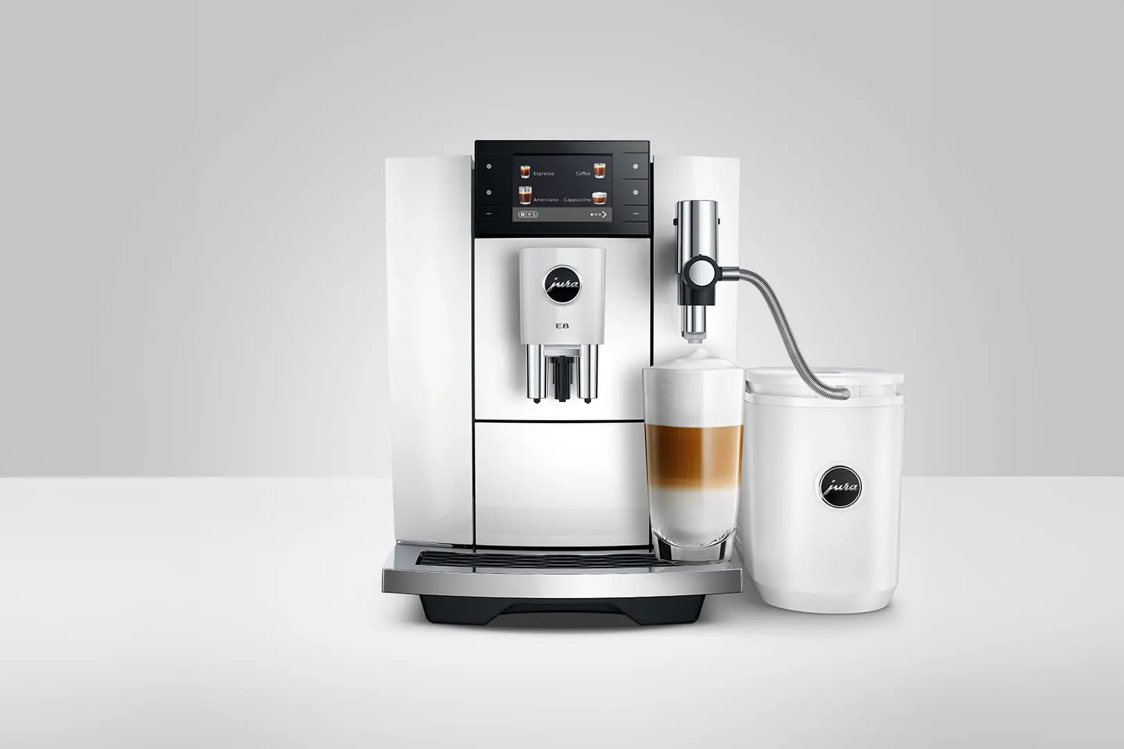 Una macchina da caffè bianca con un bicchiere di latte macchiato e un contenitore del latte.