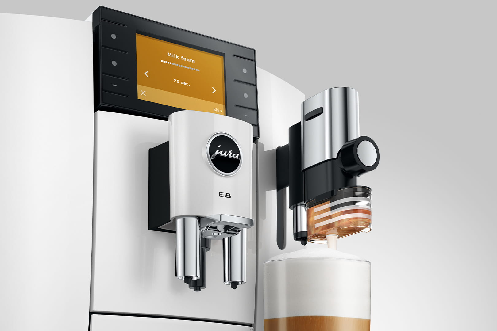 Una macchina da caffè bianca con montalatte che eroga schiuma in un bicchiere.