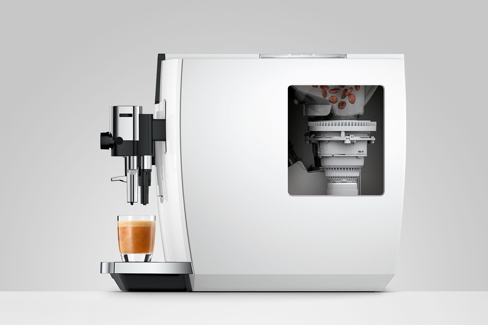 Una macchina da caffè bianca con un bicchiere di espresso e chicchi di caffè visibili all'interno.