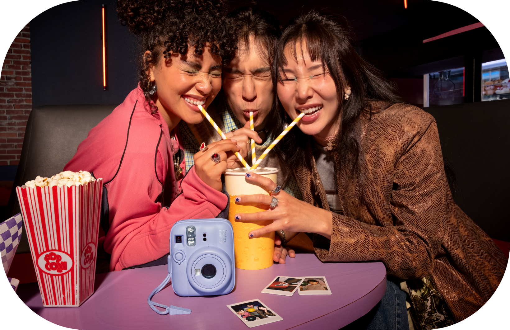 Drei Freunde teilen sich ein Getränk im Kino mit Popcorn und einer Kamera.