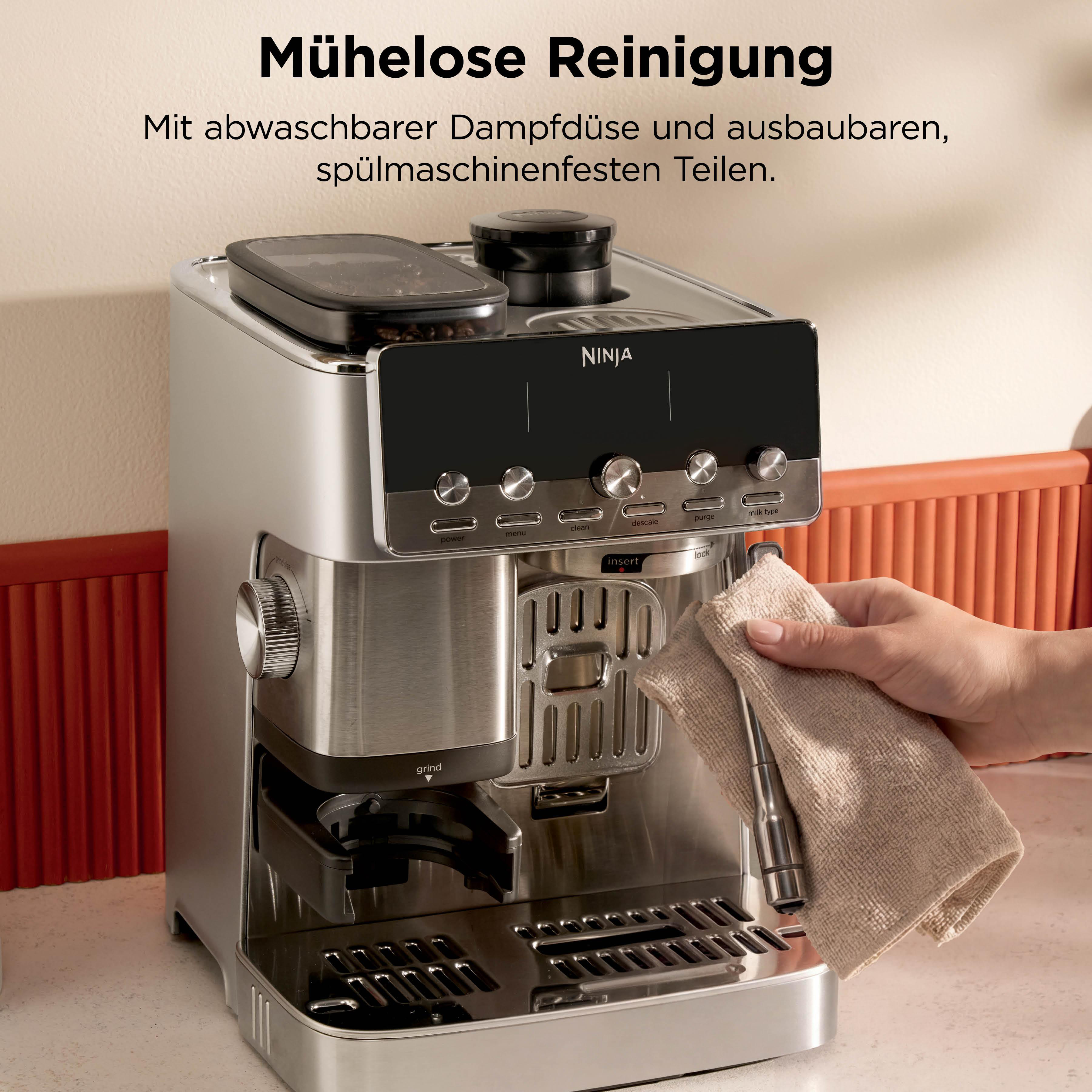 Eine Hand reinigt eine silberne Kaffeemaschine mit einem beigefarbenen Tuch.