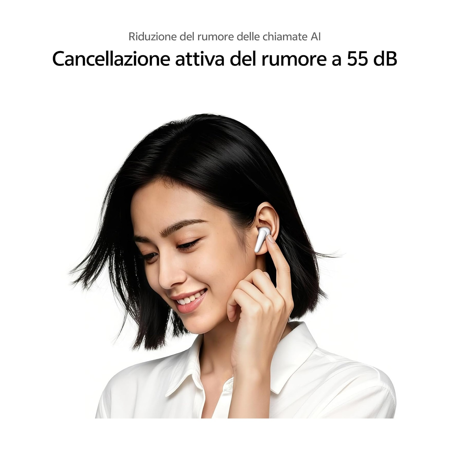 Una donna con auricolari, si tocca l'orecchio. Indossa una camicia bianca.