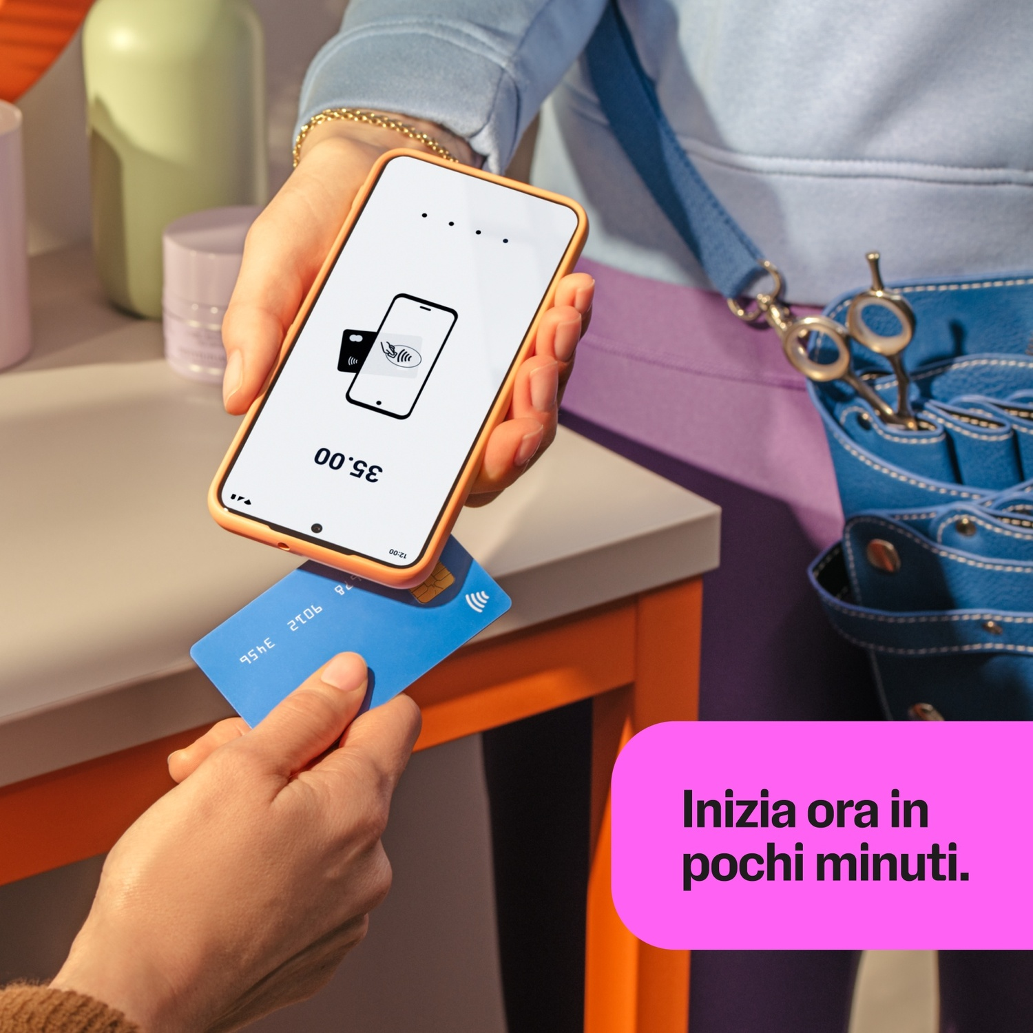 Una mano tiene uno smartphone con un'app di pagamento. Un'altra mano tiene una carta blu.