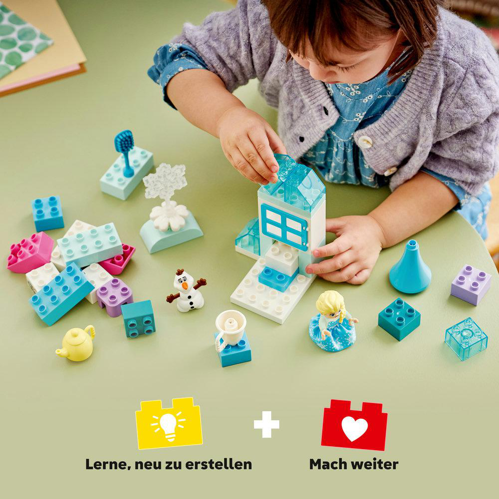 Ein Kind baut mit bunten Lego-Steinen ein kleines Haus, Schneemann und eine Figur.