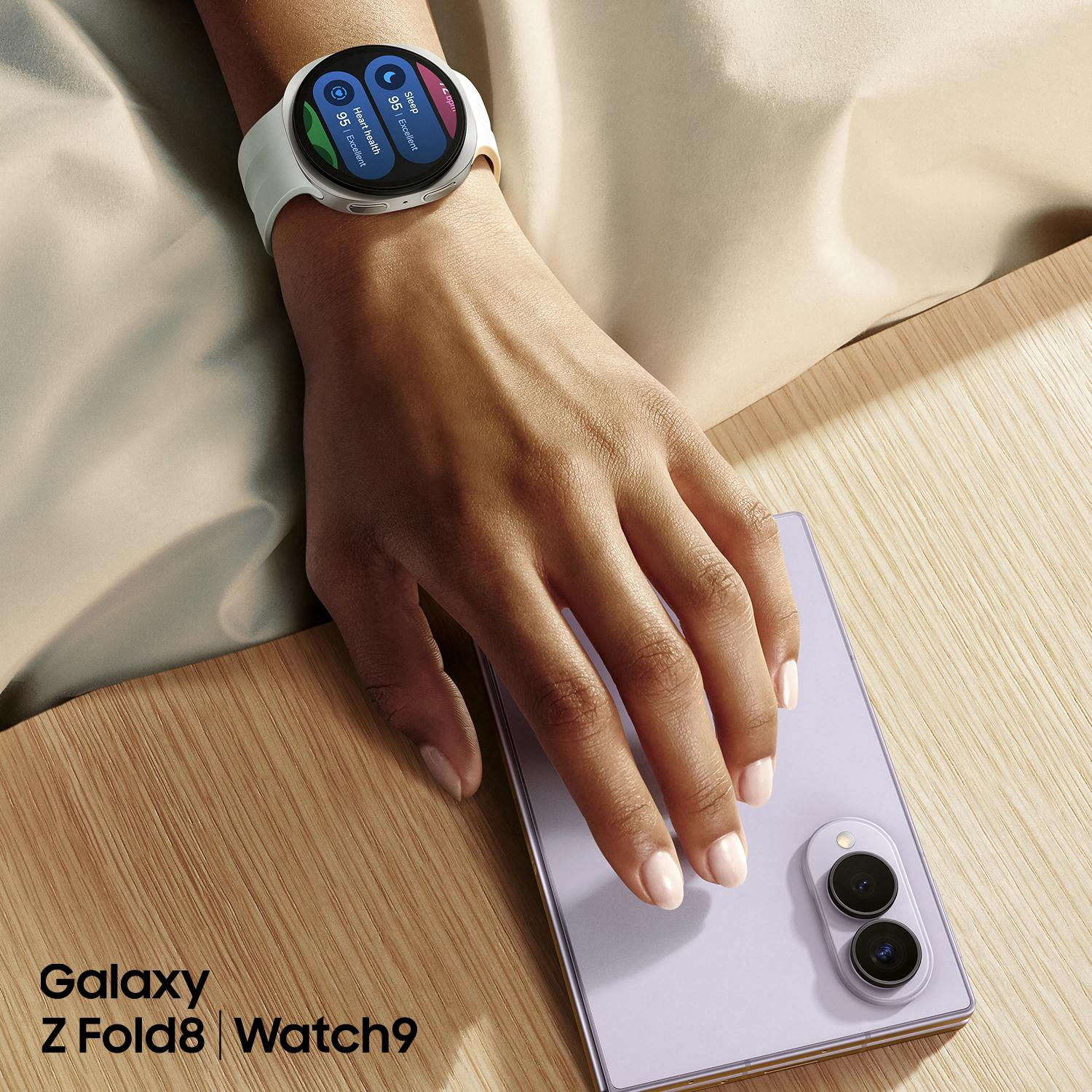 Eine Hand trägt eine weiße Smartwatch und legt sie neben ein lila Smartphone.