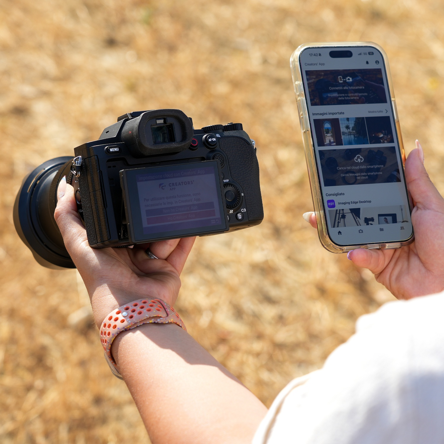 Une personne tient un appareil photo et un smartphone affichant une application.