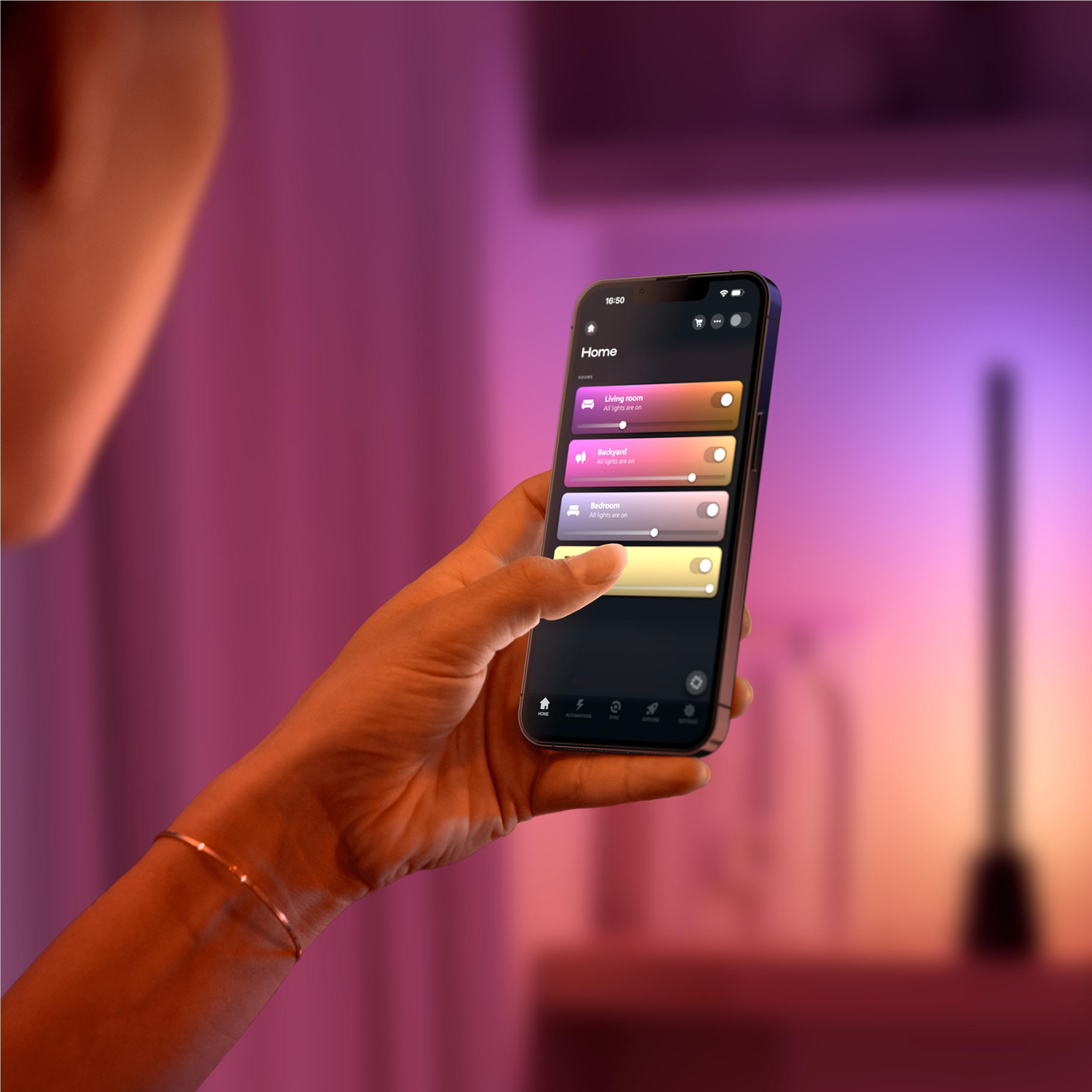 Eine Hand hält ein Smartphone mit einer App zur Steuerung von Lichtern in verschiedenen Räumen.
