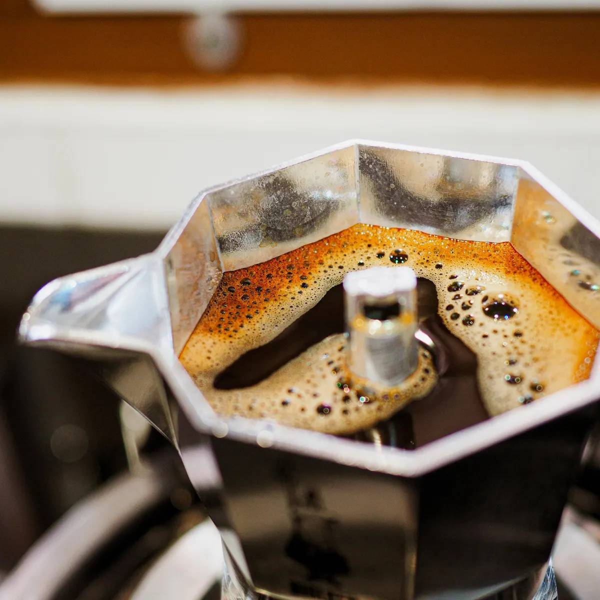 Una cafetera moka con café recién hecho y espuma.