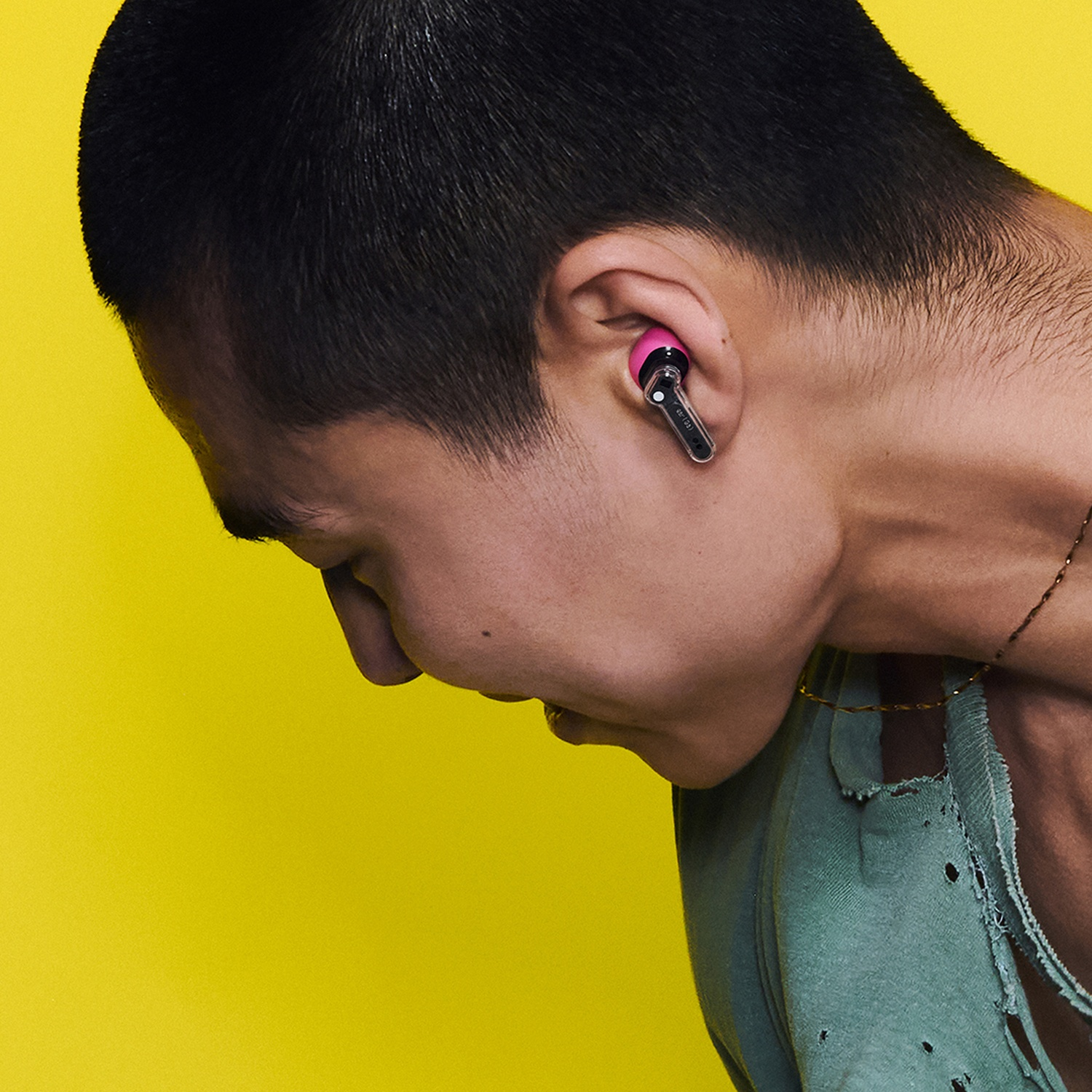 Uomo con auricolare rosa e trasparente su sfondo giallo.
