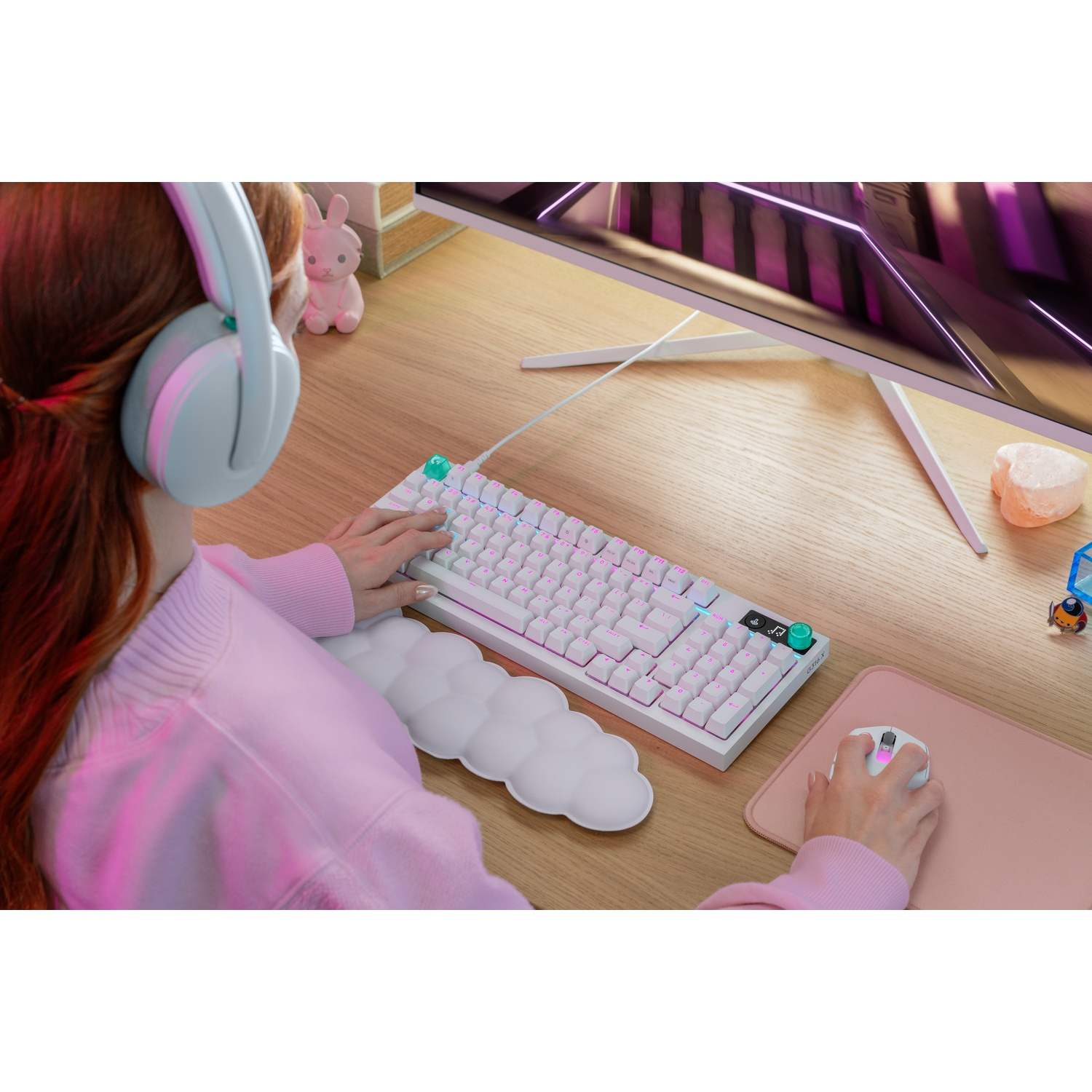 Una persona con cuffie digita su una tastiera bianca, con un mouse nelle vicinanze.