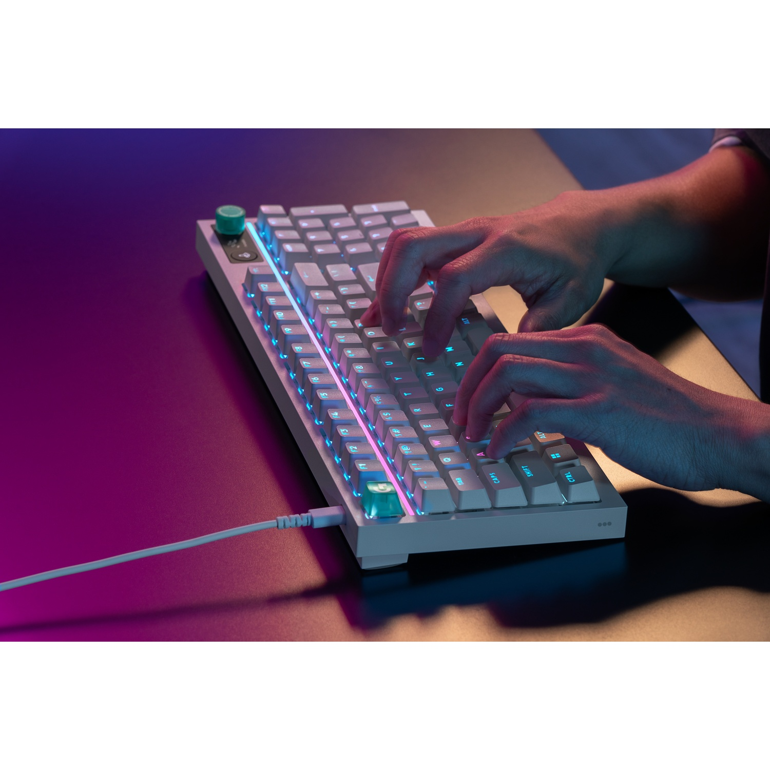 Mani che digitano su una tastiera meccanica bianca con retroilluminazione RGB, collegata.
