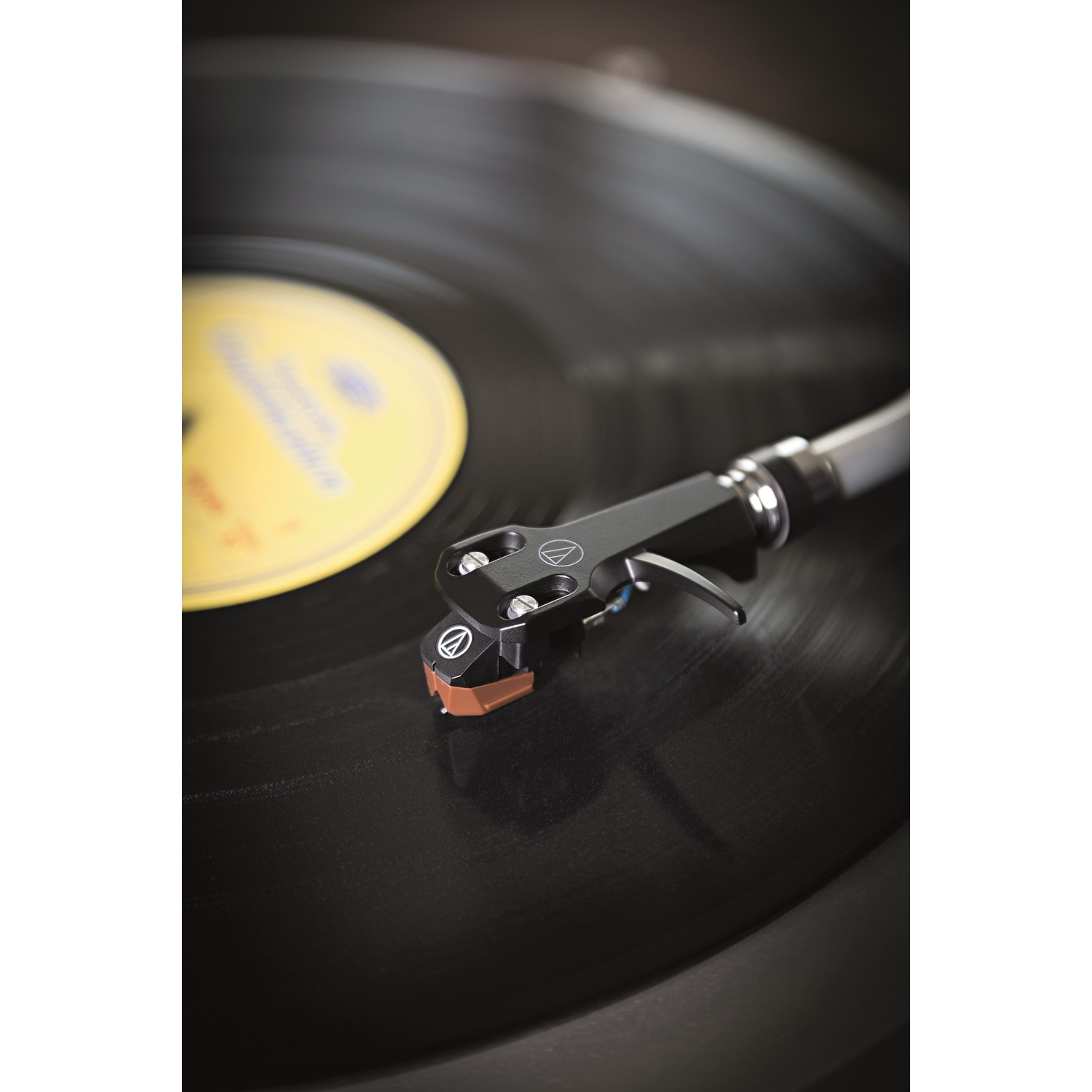 Braccio del giradischi si abbassa su un disco in vinile nero con etichetta gialla.