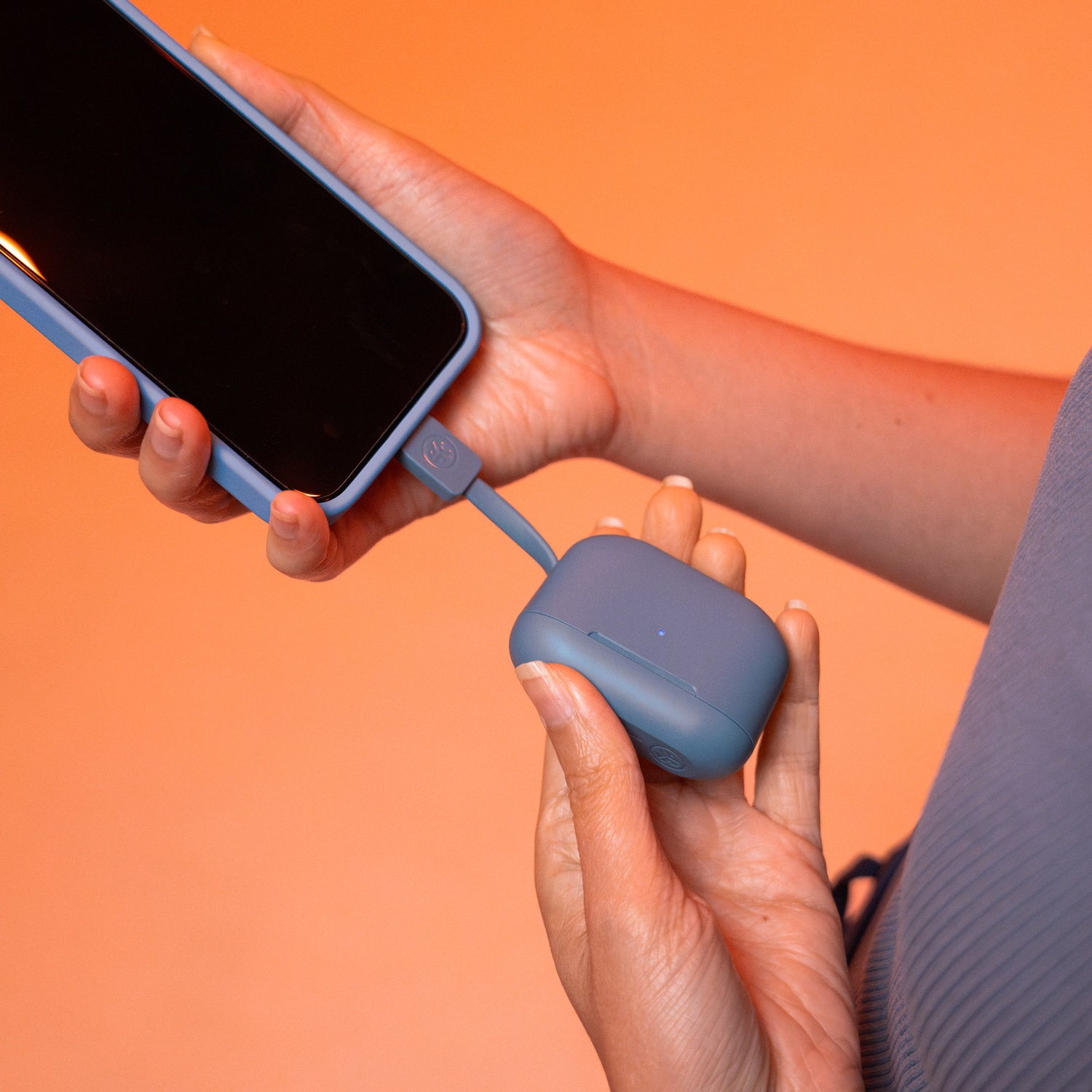 Personne chargeant un téléphone bleu avec un étui de chargement bleu grisé.