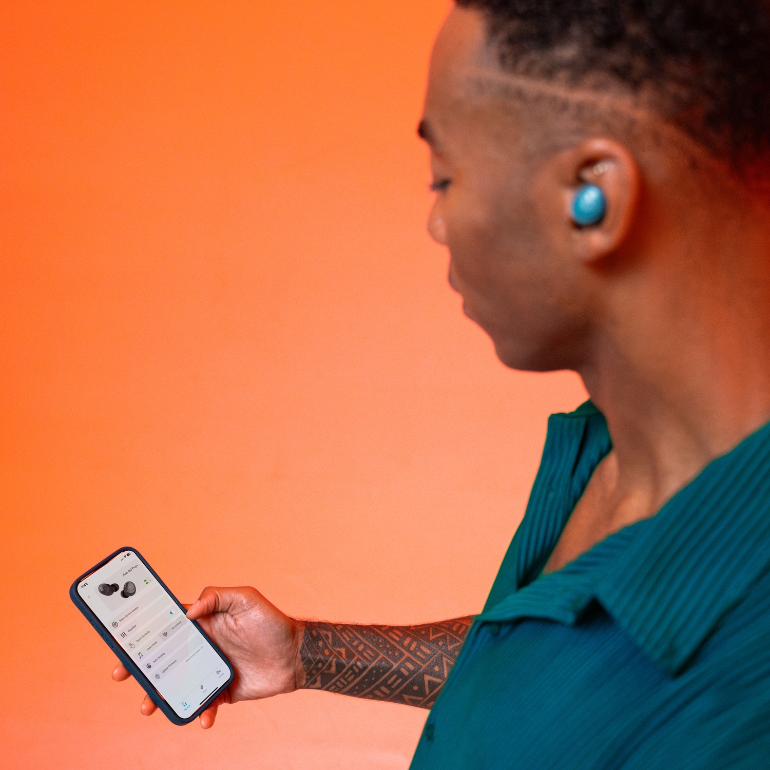 Homme avec écouteur bleu tient un smartphone affichant les paramètres des écouteurs.
