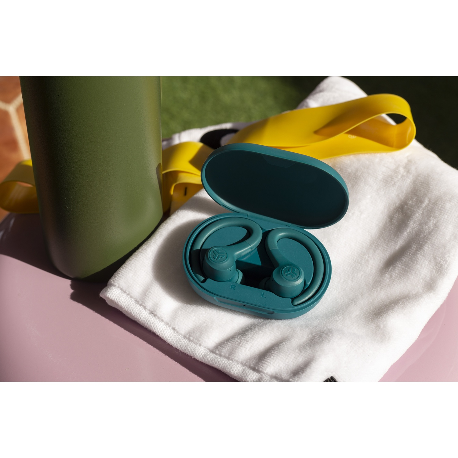 Groene waterfles, witte handdoek, gele band en teal oordopjes in hoesje.