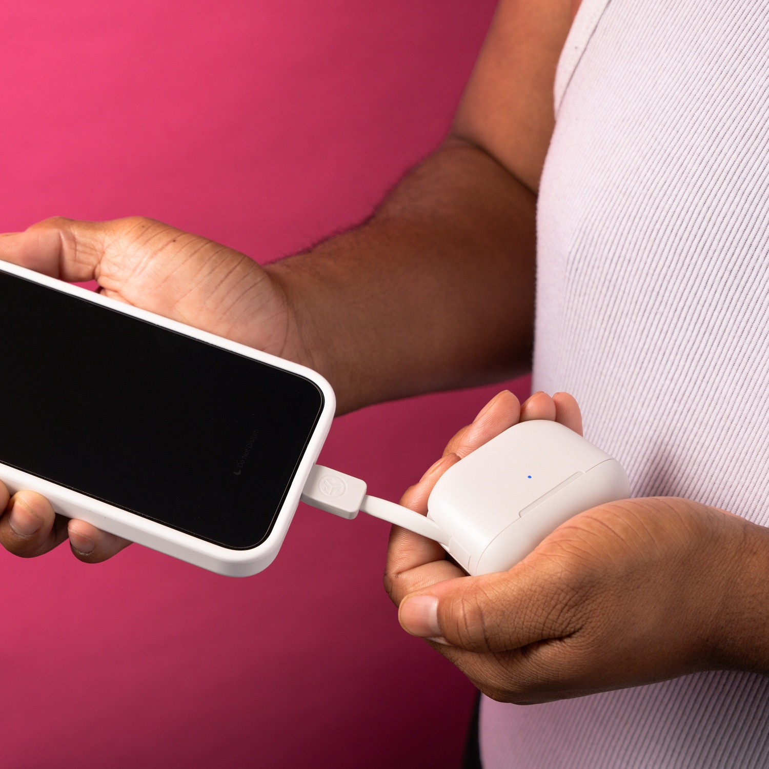 A person holds a white smartphone and a white wireless earbud charging case.
