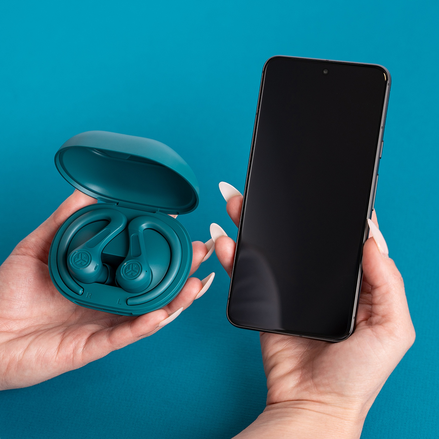 A hand holds a teal charging case with earbuds, another holds a black smartphone.