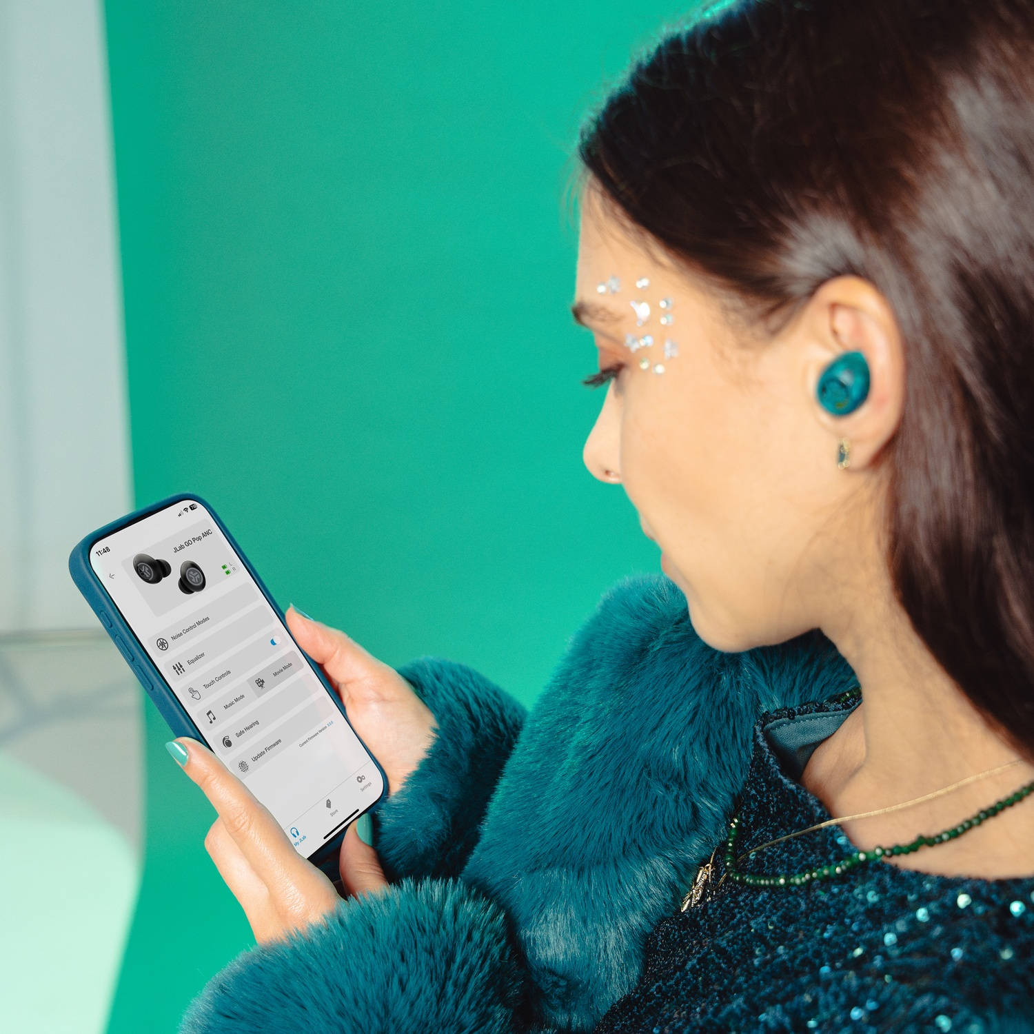 Een vrouw met teal oordopjes en gezichtsgitter gebruikt een smartphone.