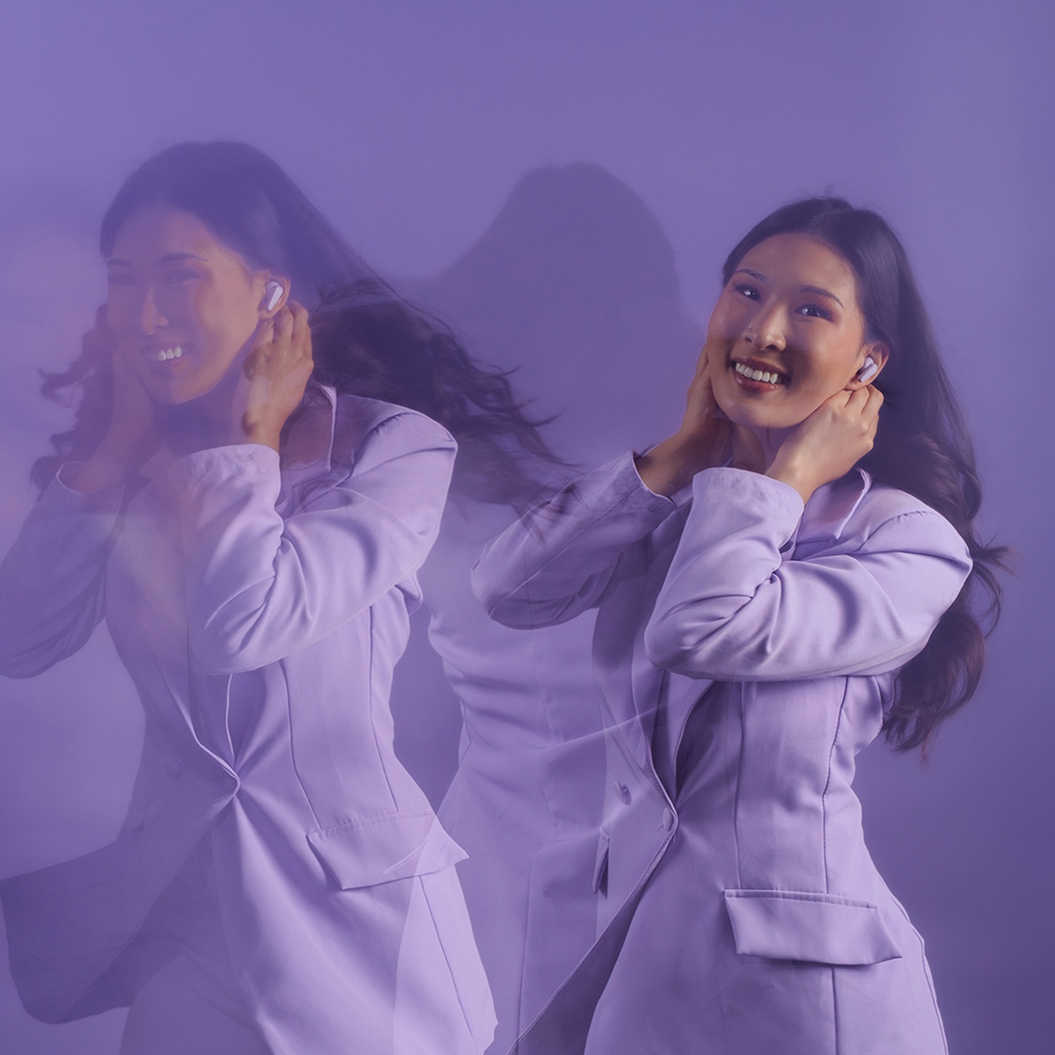 Une femme en blazer lilas avec des écouteurs sourit, son image floue et répétée.