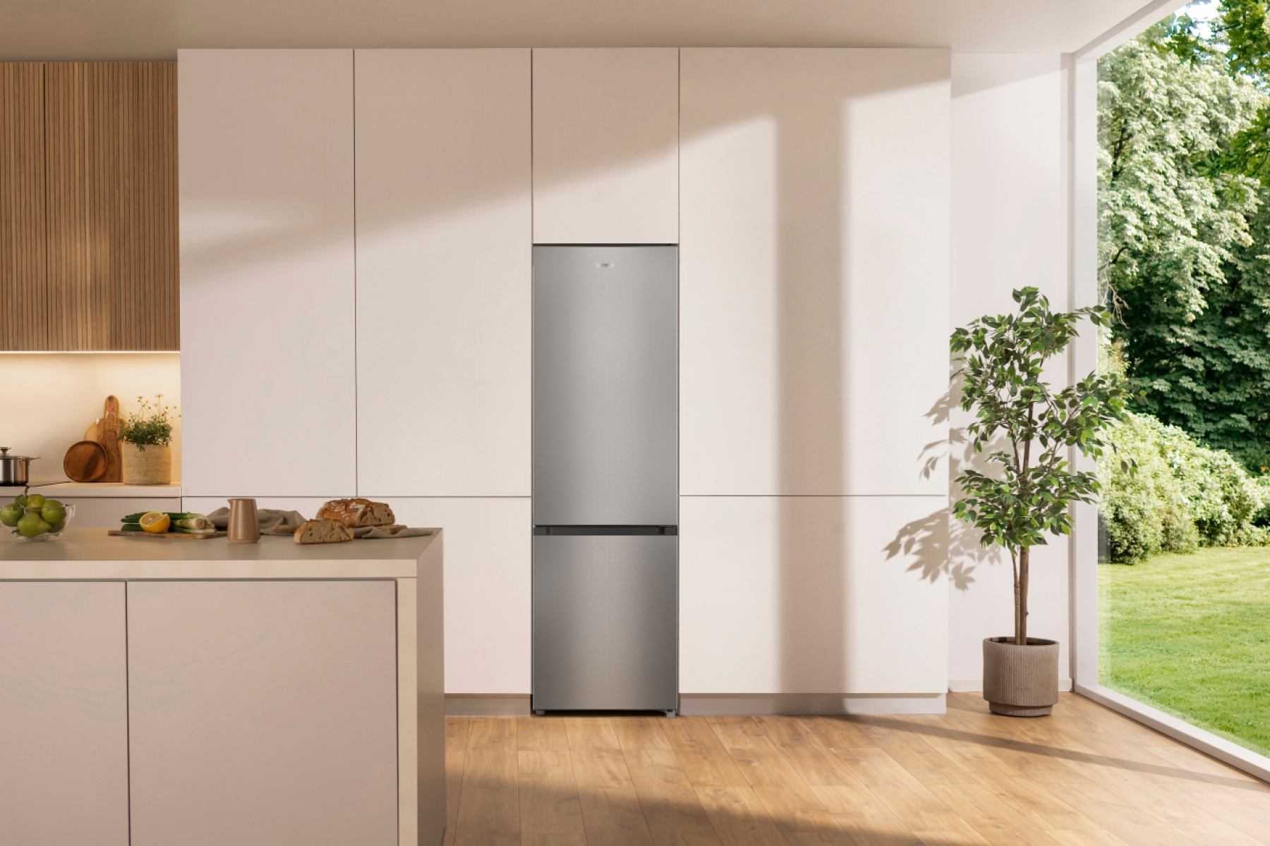 Moderne Küche mit silbernem Kühlschrank, Arbeitsplatte und einem grünen Baum.