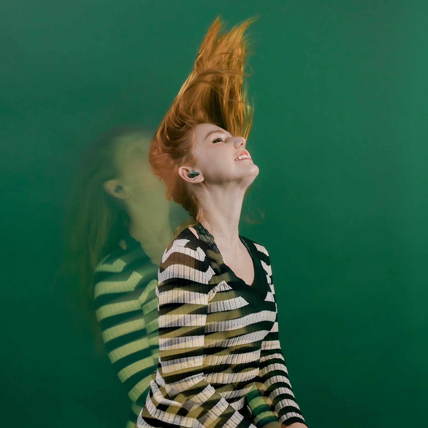 Une femme aux cheveux roux secoue la tête, ses cheveux volent vers le haut.