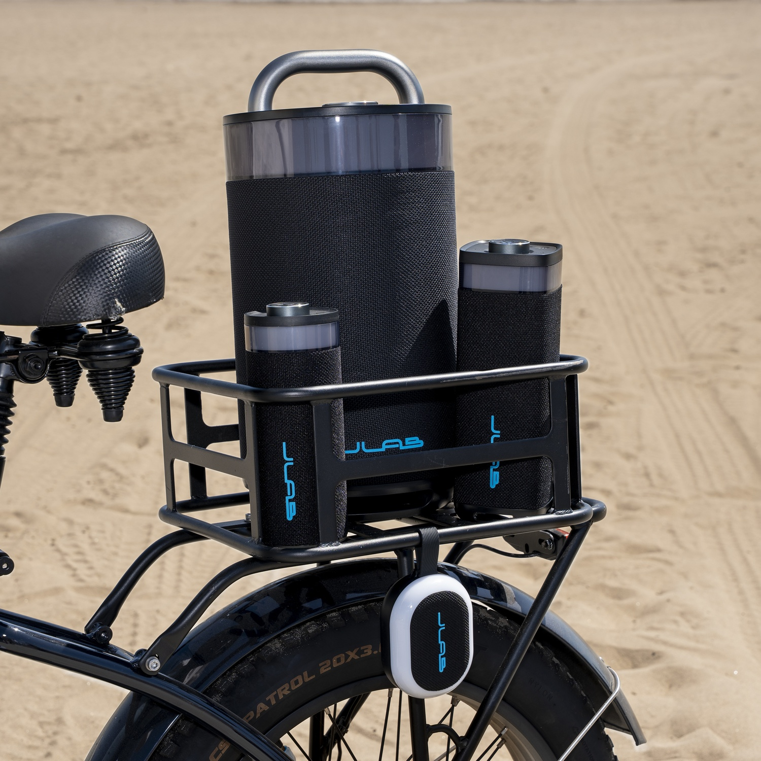 A black speaker set on a bicycle rack at the beach.