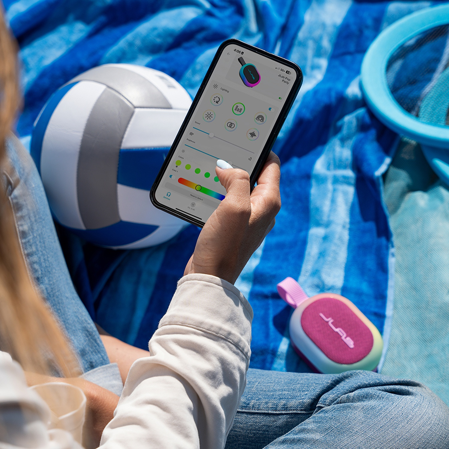 A person holds a smartphone with an app, next to a volleyball and a speaker.