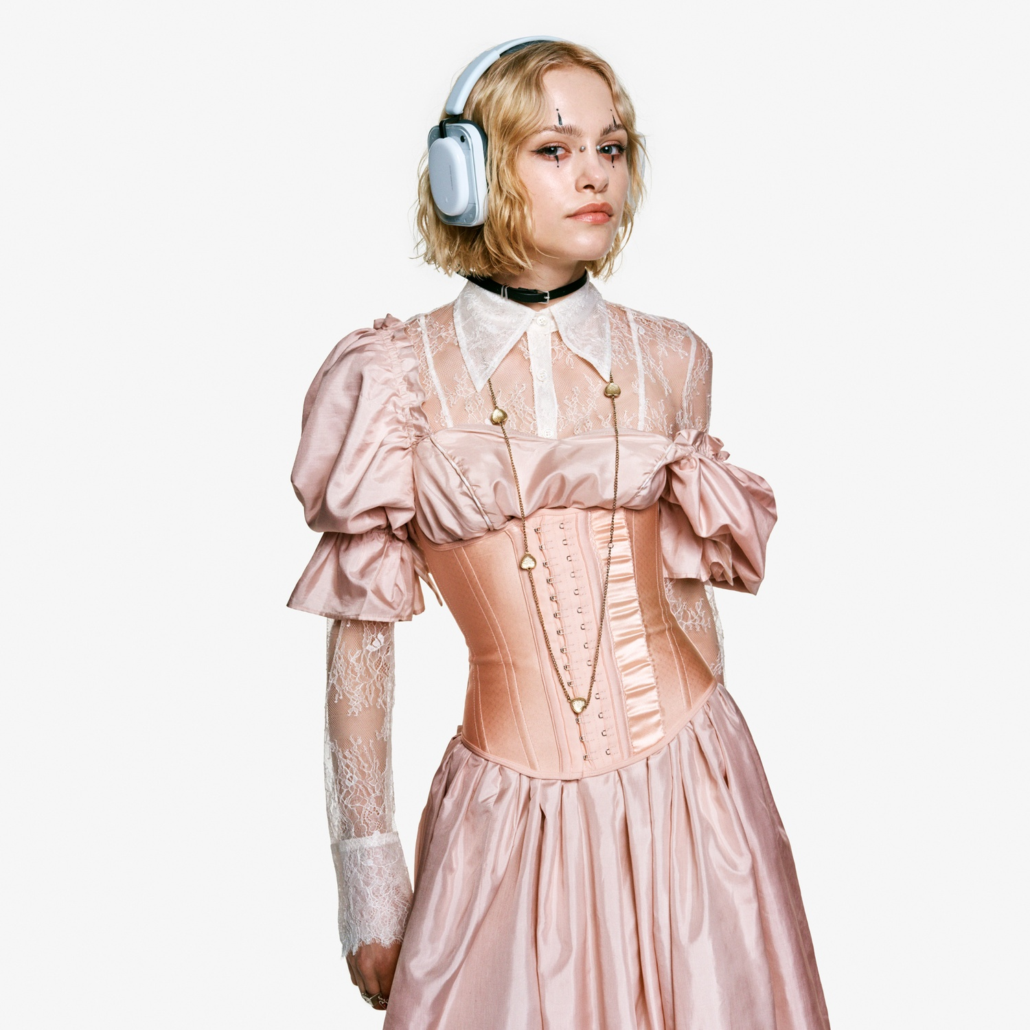 Una donna bionda indossa cuffie e un vestito rosa.