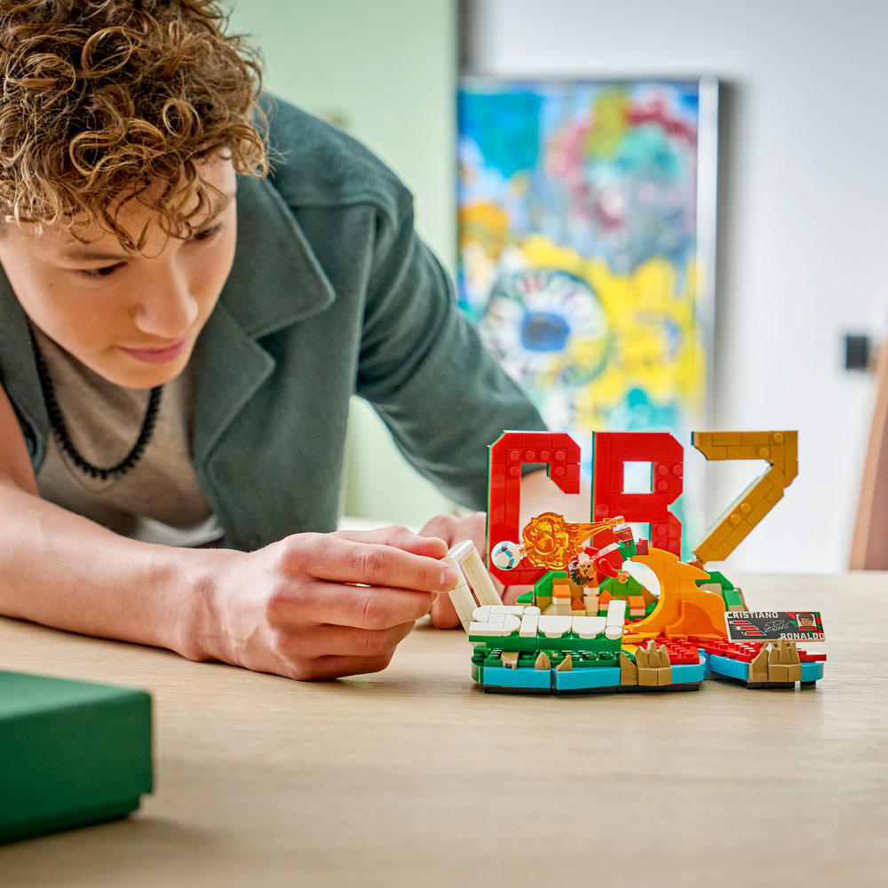 Ein Junge baut ein Lego-Modell mit CR7 und einem Fußballspieler.