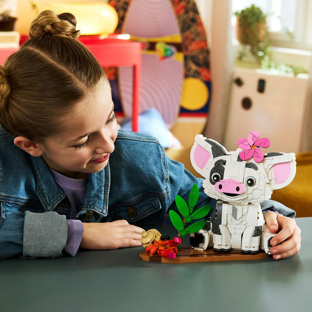 Ein Mädchen mit einem blauen Jeanshemd schaut auf ein Lego-Schwein und eine Krabbe.