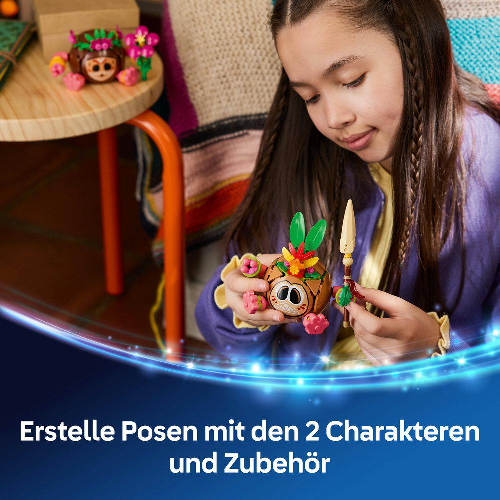 Ein Mädchen hält eine kleine, runde, braune Figur mit großen Augen und grünen Blättern.