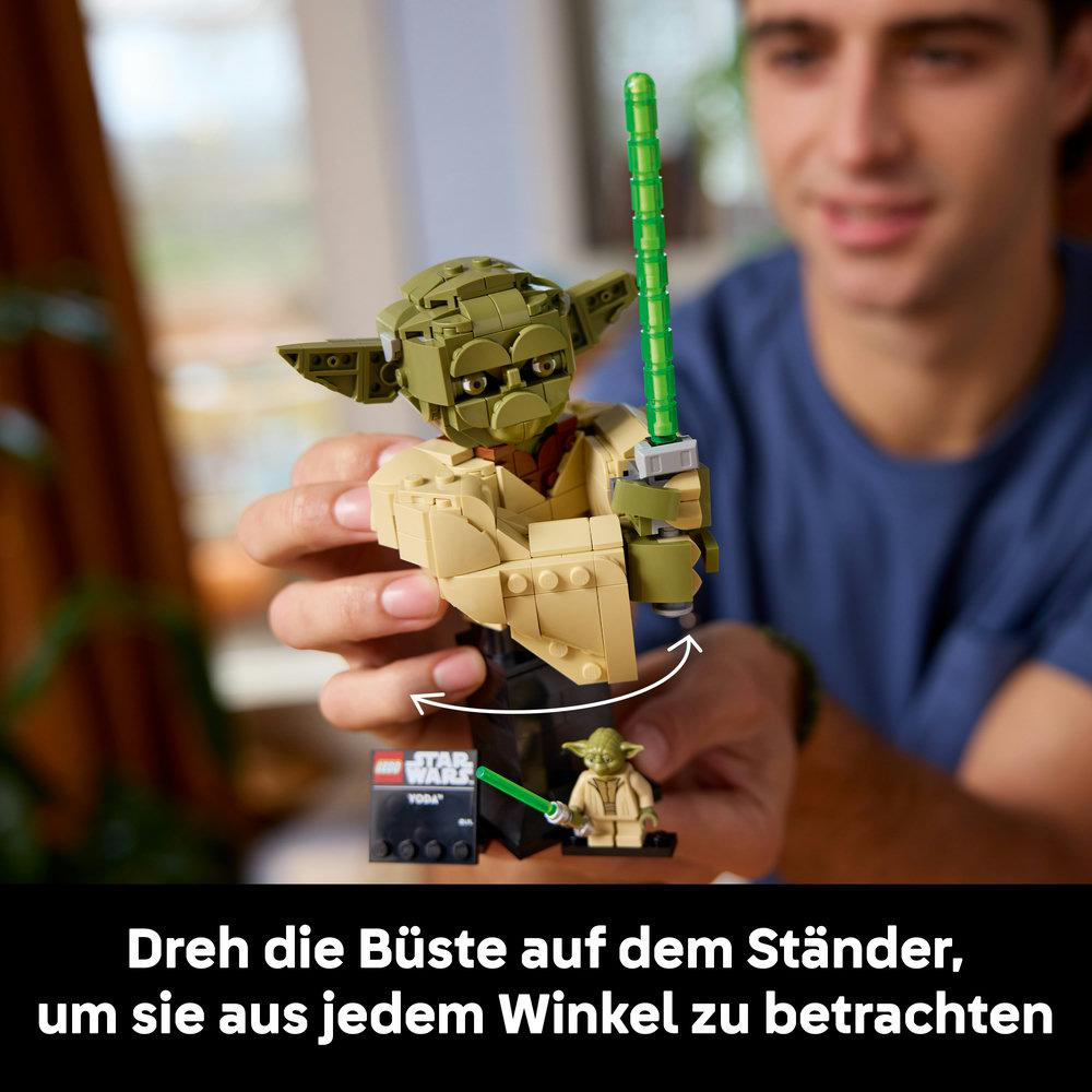 Eine Person dreht eine LEGO Yoda-Büste mit einem grünen Lichtschwert auf einem Ständer.