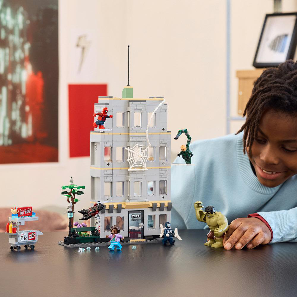Ein Kind spielt mit einem Lego-Set eines Hochhauses mit Superheldenfiguren wie Spiderman und Hulk.