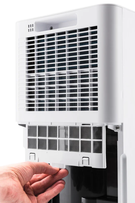 Egy kéz fehér szűrőt húz ki egy fehér ventilátorból.