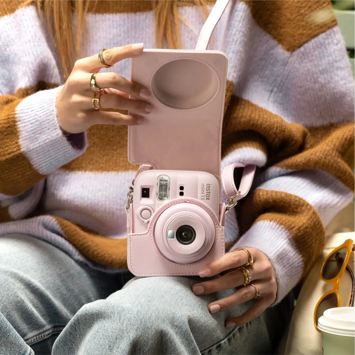 Une personne tient un appareil photo instantané rose avec son étui.